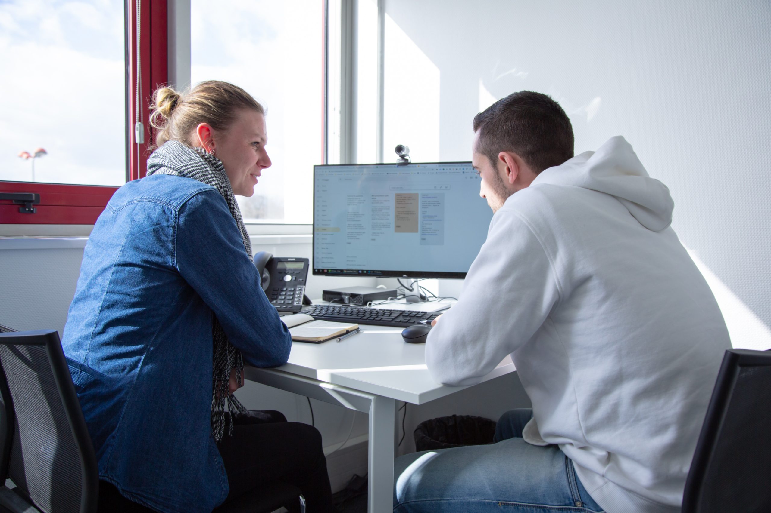 Deux collaborateurs de notre agence digitale de Rennes en réunion face à un ordinateur présentant un planning