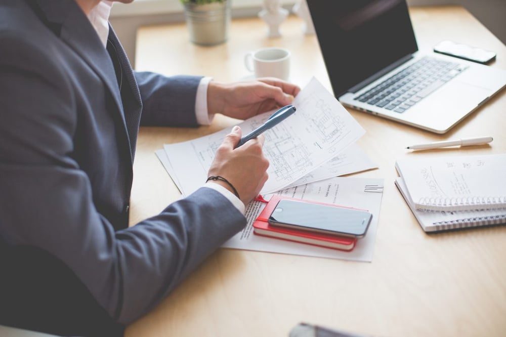 Photo d'illustration, gros plan sur le buste d'une personne, en veste de tailleur, les coudes sur un bureau